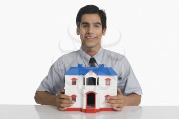 Real estate agent holding a model home and smiling