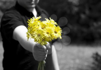 Man giving a present with yellow daisy flowers. Focus on flowers.