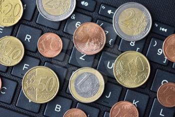 Euro coins lie on the laptop keyboard in black, close-up, symbol of working on the Internet or online payment for purchases, space for text