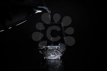 pouring water in a clear glass on a black background