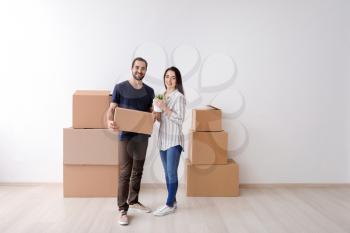 Young couple with boxes and houseplant indoors. Moving into new house�