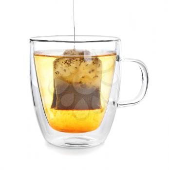Brewing of hot beverage with tea bag in glass cup on white background�