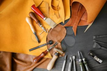 Leather with craft tools on dark wooden background�