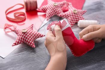 Child making felt Christmas toy at wooden table�