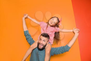 Funny portrait of father and his little daughter on color background�