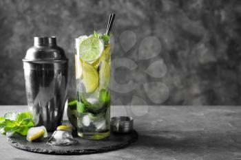 Cocktail shaker and glass of fresh mojito on table�