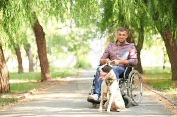 Young man in wheelchair and his service dog outdoors�