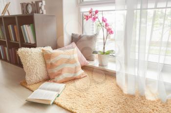 Cozy place for rest with soft pillows and book near window�