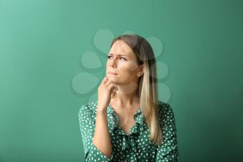 Thoughtful young woman on color background�