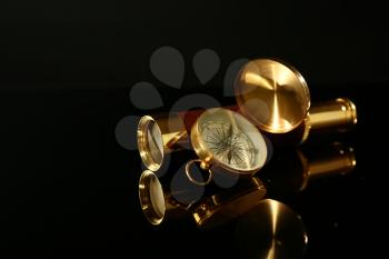 Golden spyglass with compass on black background�