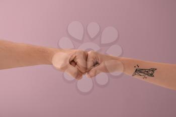 Man and woman making fist bump gesture on color background�