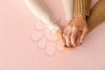 Loving young couple holding hands on color background�