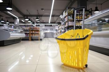 Shopping basket in interior of modern grocery store�