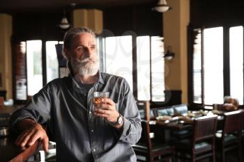 Senior man drinking whiskey in pub�
