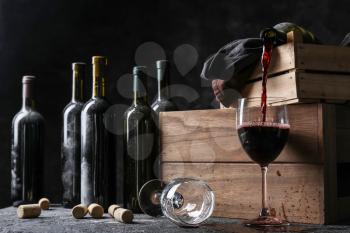 Pouring of red wine from bottle into glass on table�