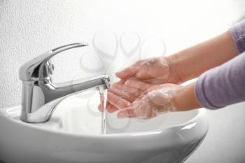 Woman washing hands in bathroom�