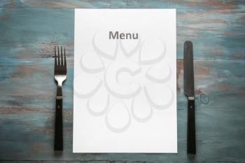 Blank menu with cutlery on wooden table�