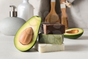 Soap bars with cut avocado on white table�