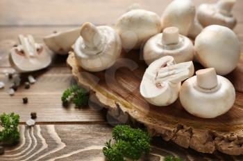 Board with fresh mushrooms on wooden table�