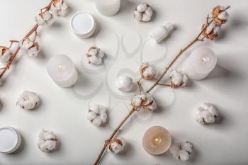 Flat lay composition with burning candles, cotton flowers and cosmetics on white background�