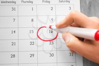 Female hand encircling date in calendar, closeup�