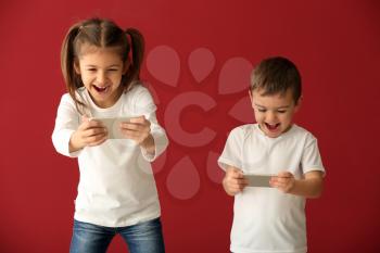 Cute little children playing with smartphones on color background�