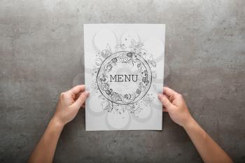 Female hands with menu on grey background�