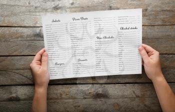 Female hands with menu on wooden table�