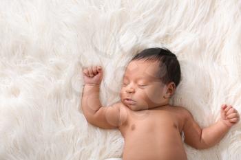 Portrait of sleepy African-American baby on light furry background�