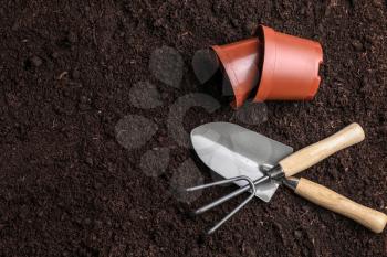 Gardening tools with pots on soil�