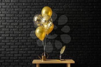 Table with decor and balloons near dark brick wall�