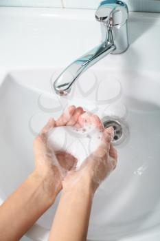 Woman washing hands in sink�