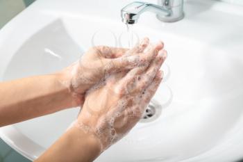 Woman washing hands in sink�