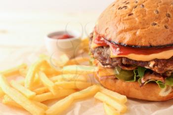 Tasty burger and french fries on table, closeup�