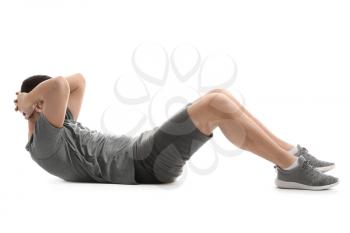 Sporty young man doing crunches against white background�