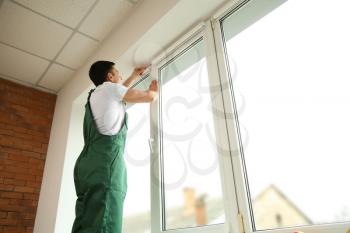 Young worker repairing window in flat�