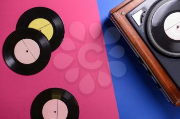 Record player with vinyl discs on color background�