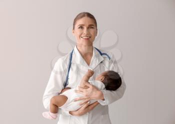 Pediatrician with African-American baby on light background�