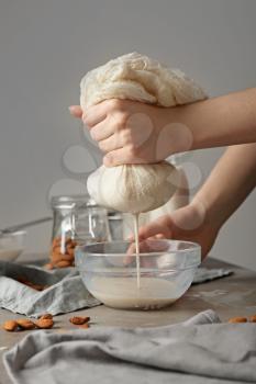 Woman making healthy almond milk in kitchen�