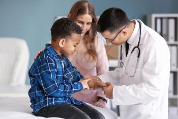 Pediatrician examining African-American boy in clinic�