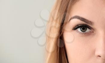 Young woman with beautiful eyelashes on light background, closeup�