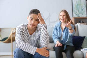 Sad African-American teenage boy having argument with his mother at home�