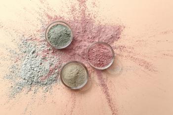 Cosmetic clays in bowls on color background�