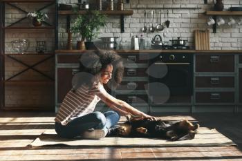 African-American woman with cute funny dog at home�