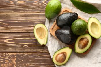 Board with fresh avocado on wooden background�