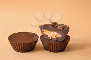 Tasty chocolate peanut butter cups on color background�