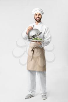 Handsome male chef with salad on white background�