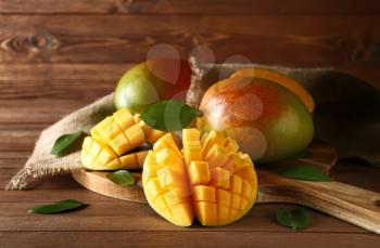 Board with tasty fresh mango on wooden table�