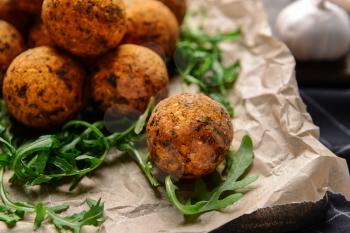 Tasty falafel balls and arugula on parchment, closeup�