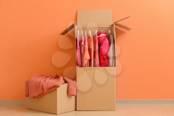Wardrobe boxes with clothes near color wall�